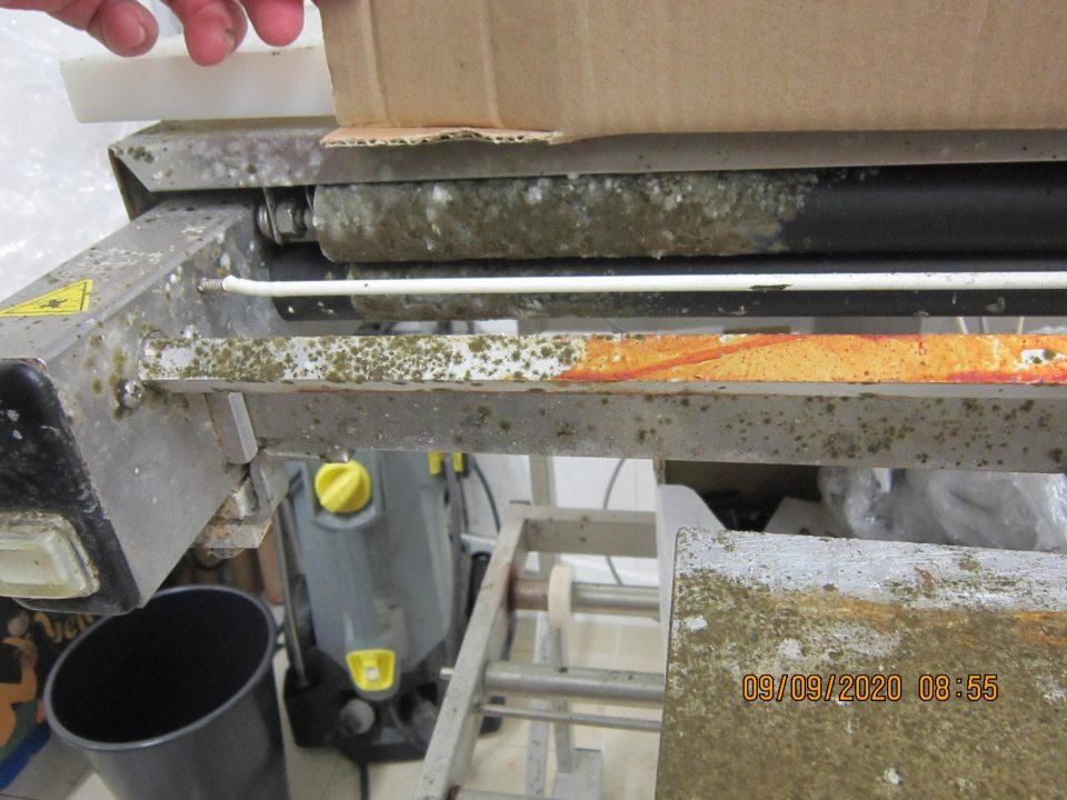 Znečistený a plesňami pokrytý baliaci stroj v sklade ovocia a zeleniny.