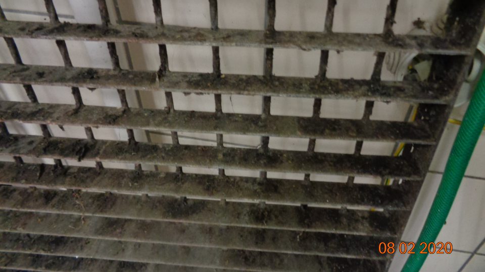  Mriežky nad výlevkou znečistené nánosom starej čiernej špiny.