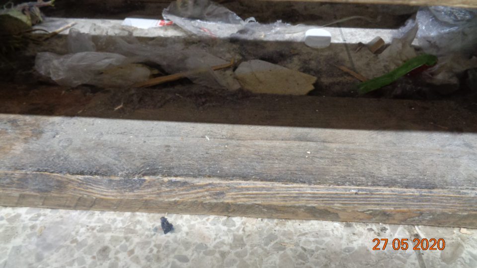  Podlaha na predajnej ploche pod paletou s uloženým UHT mliekom znečistená vrstvou prachu, zvyškami obalov, kartónov, papierikmi a plastovými uzávermi od nápojov.