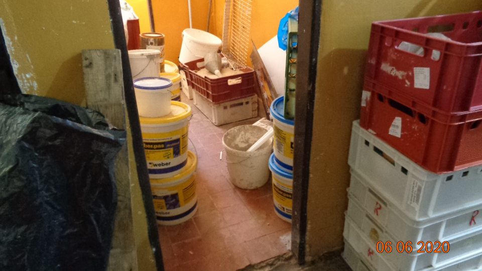  V celej pravej časti skladu na prízemí prítomný stavebný materiál ( plasové vedrá, prepravka s pieskom, kovové konštrukcie, naplnené plastové vrecia ).