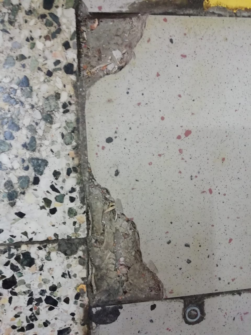 Poškodená podlaha v priestore dverí medzi predajňou a skladom.