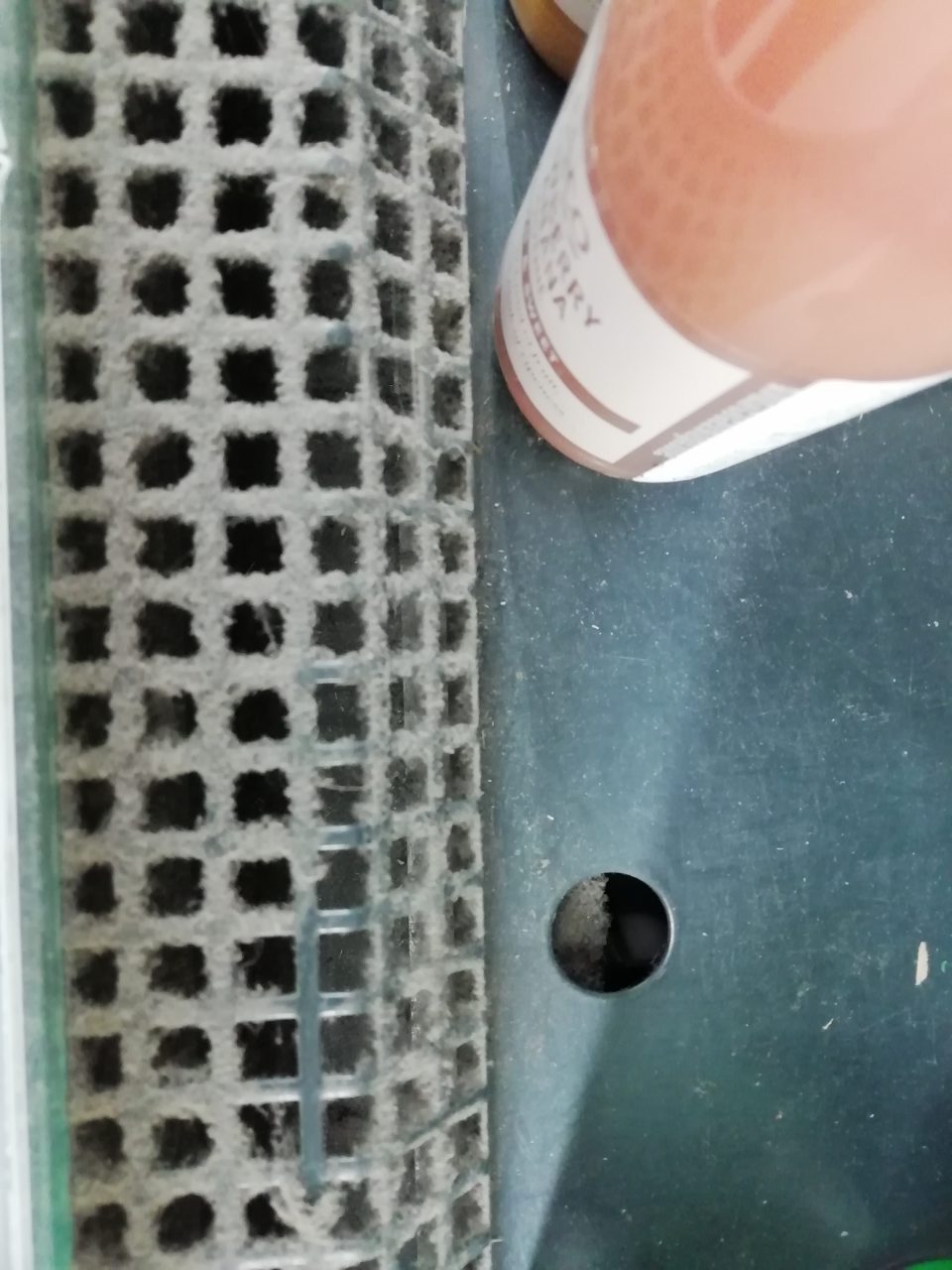 Znečistená mriežka od prachu chladiacej vitríny pre nealkoholické nápoje a bagety.