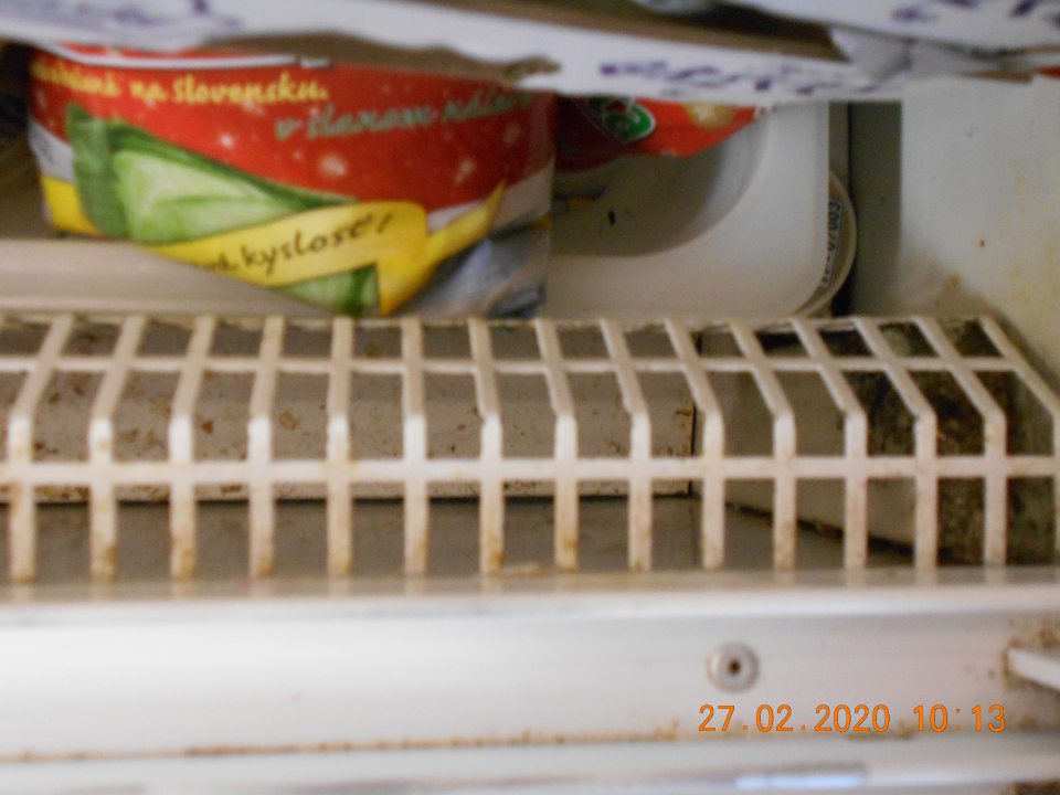Znečistená a skorodovaná chladiarenská vitrína pod mriežkou.