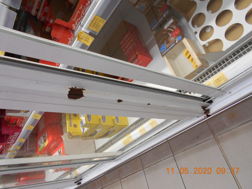 Skorodovaná vonkajšia časť chladiaceho zariadenia s uchovávanými mliečnymi výrobkami na viacerých miestach