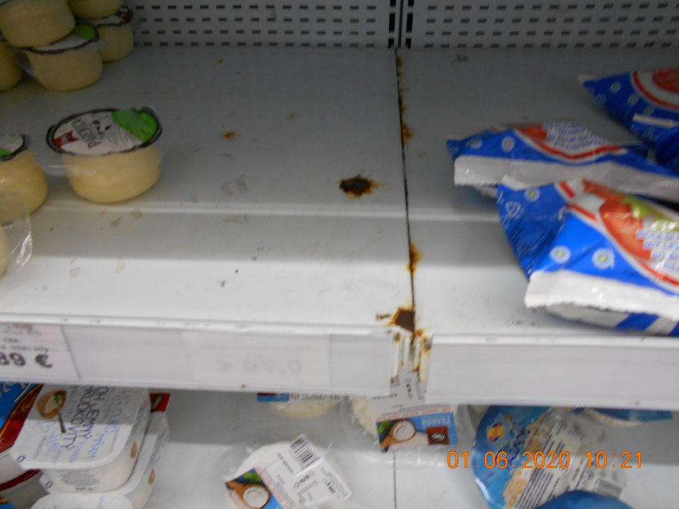 Zistený olupujúci sa náter políc, ako aj dno pod mriežkami a vonkajší rám dverí chladiarenského zariadenia s uchovávanými mliečnymi výrobkami na predajnej ploche.