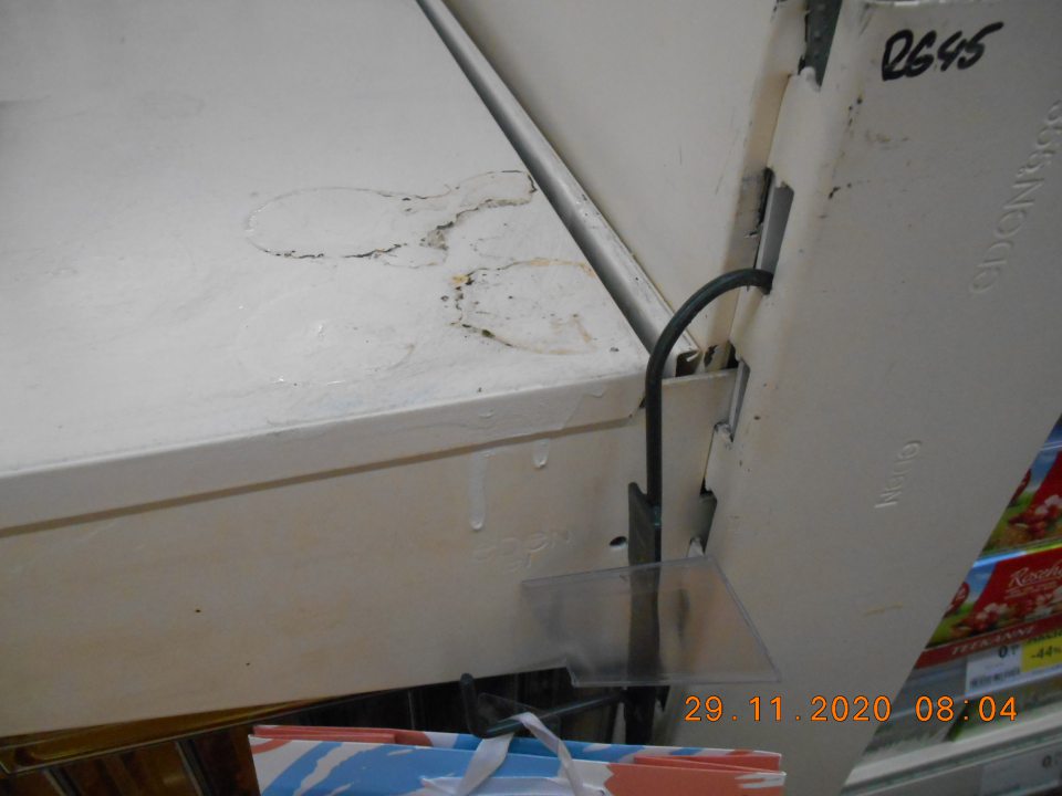 Znečistený regál na predajnej ploche, na ktorom sú umiestnené cukrovinky.