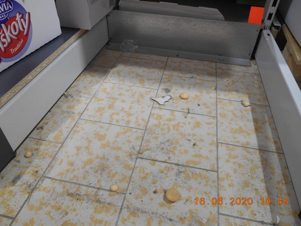 Na predajnej ploche pod paletami na uloženie potravinového tovaru podlaha znečistená prachom, nečistotami, rozsypaným tovarom - piškótami a kúskami papiera.