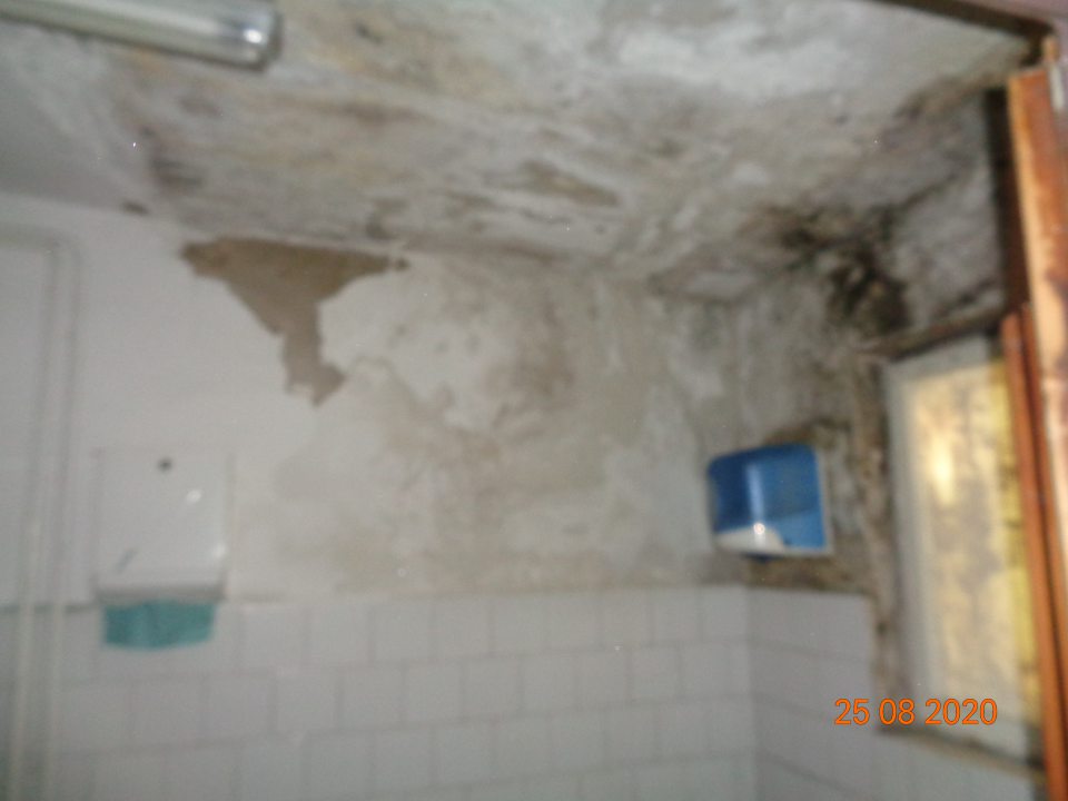 Znečistená poškodená hygienická maľba stien na sociálnom zariadení na rampe.