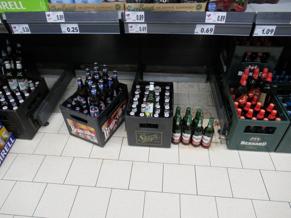 V oddelení nápojov na predajnej ploche pivové fľaše a epravky s pivom uložené priamo na podlahe. 