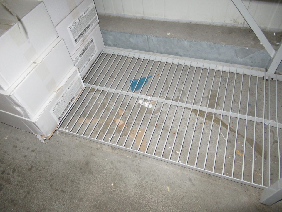 Pod regálom v mraziacom boxe, podlaha znečistená mechanickými nečistotami, zbytkami obalového materiálu a prachom. 