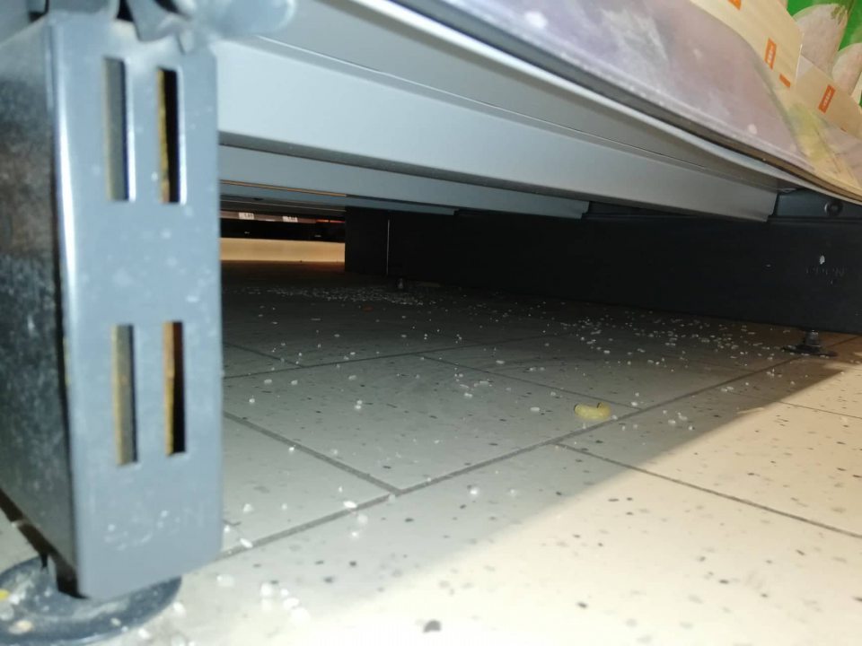 Zvyšky predávaných potravín pod regálmi na predajnej ploche.