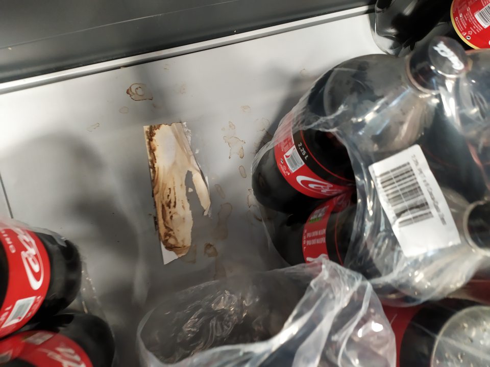 Znečistený regál pri nealko nápojoch na predajnej ploche.