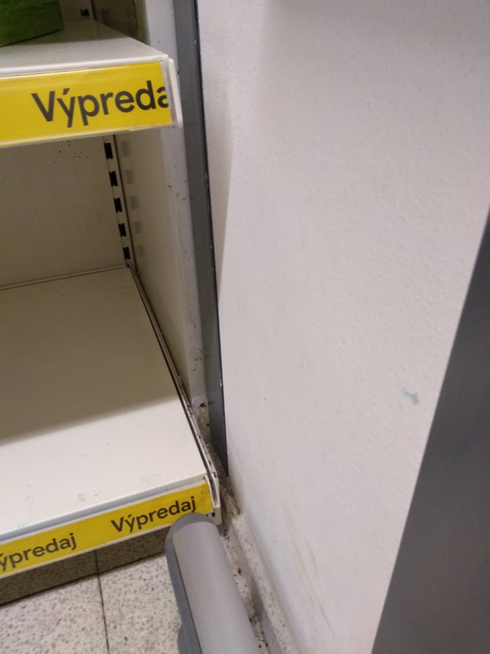 Regál na predajnej ploche, určený na výpredaj alko a nealko nápojov – na bočnej kovovej stene zastaralé zatečenie bližšie neurčeným nápojom, v spodnej časti a na podlahe hrubé nečistoty, pavučiny.