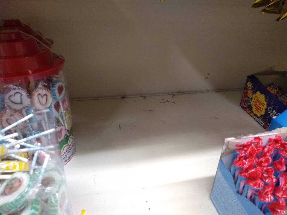 Regál s cukrovinkami na predajnej ploche – znečistenie hrubou vrstvou prachu v jeho zadnej časti.