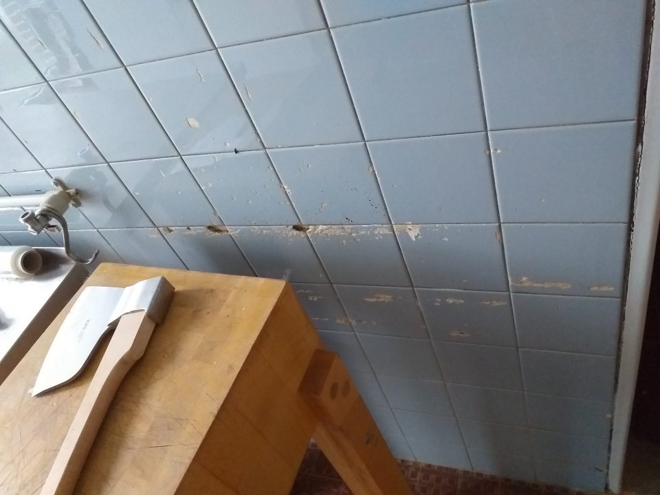 Necelistvý, poškodený povrch keramického obkladu steny v prípravovni mäsa.