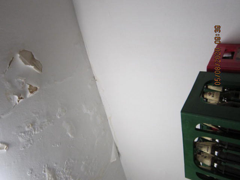 poškodený strop skladu s olupujúcou sa a opadávajúcou omietkou