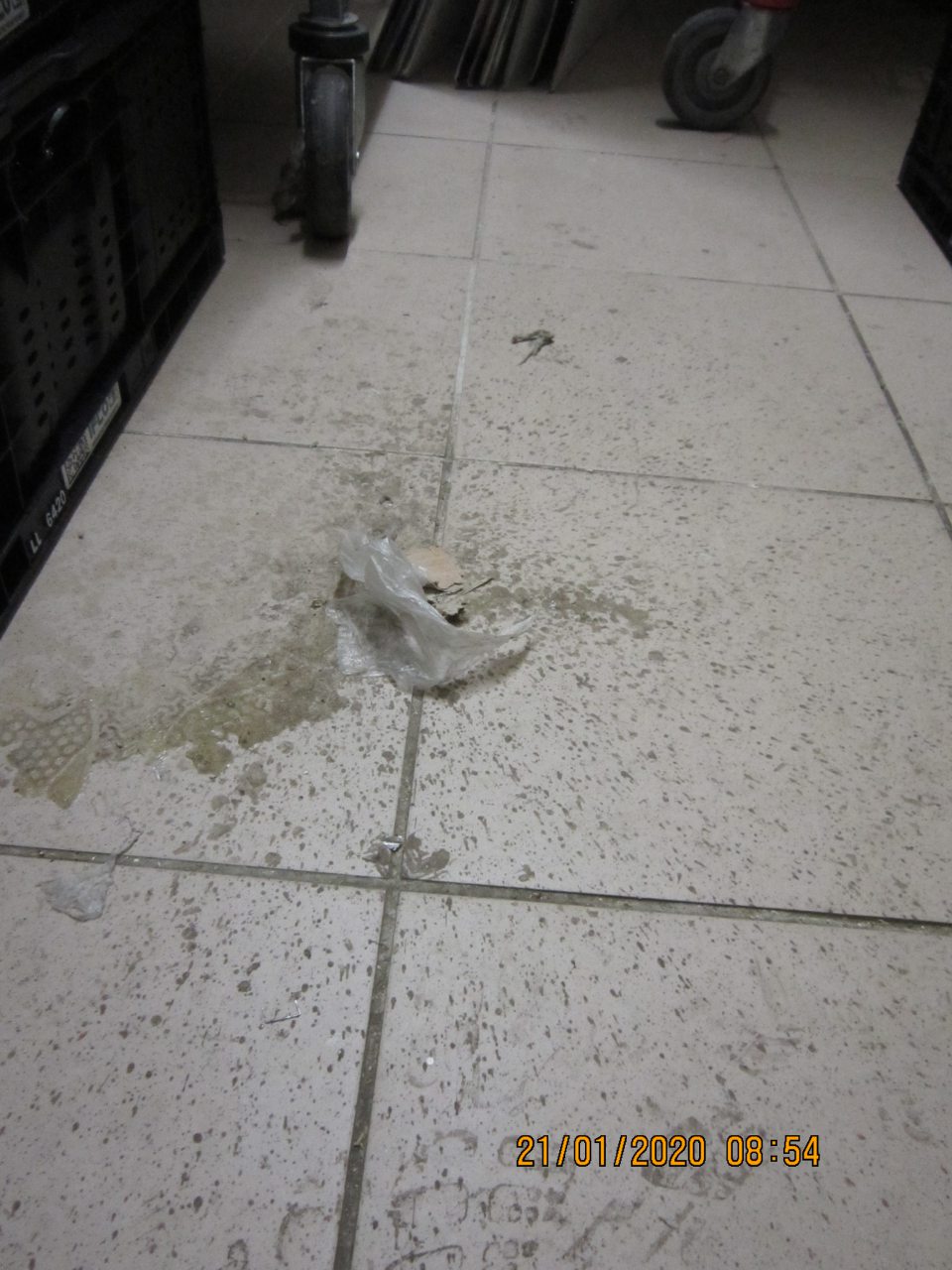 V zázemí  prevádzky v sklade alkoholu  znečistená podlaha  po rozliatej, zaschnutej tekutine  s nalepeným kúskom kartónu a plastu.