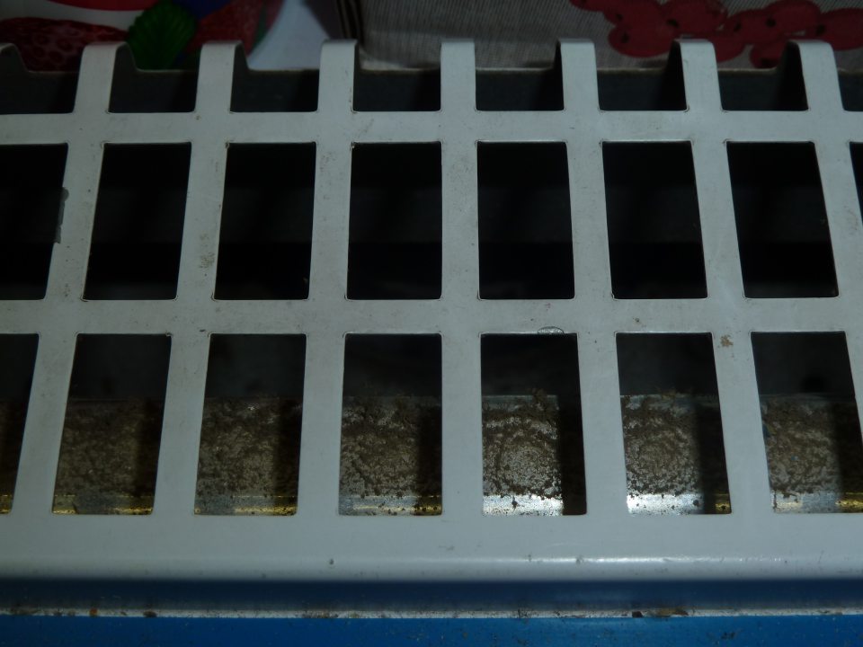 V chladiacej vitríne pre mliečne výrobky v spodnej časti pod mriežkou  vedľa ventilátora chladenia je usadená vrstva prachu.