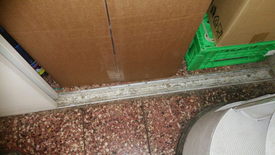 Znečistená vodiaca lišta posuvných dverí skladu obalov na oddelení lahôdok a dopeku