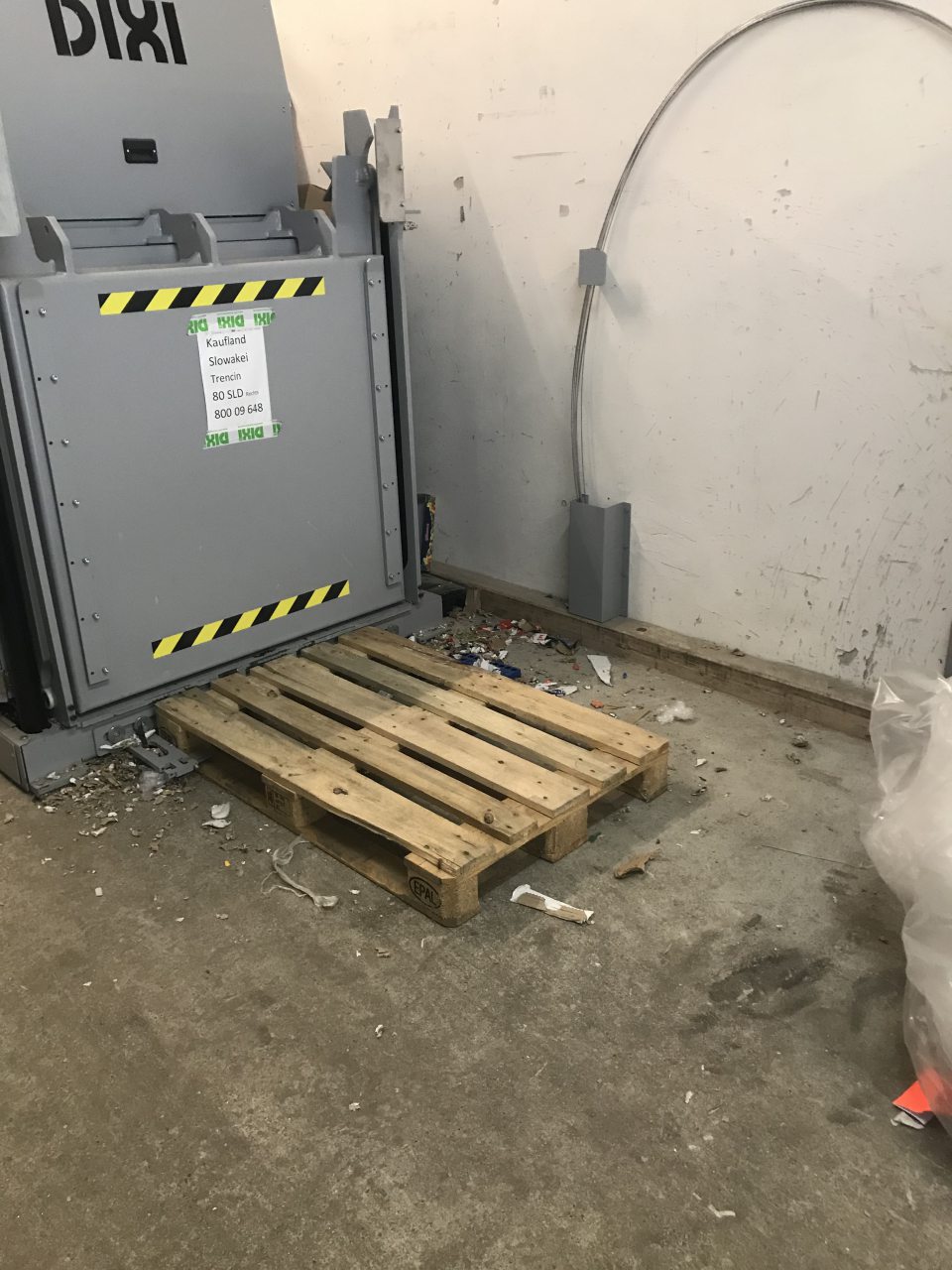 Znečistená podlaha okolo lisu na kartóny na príjmovej rampe.