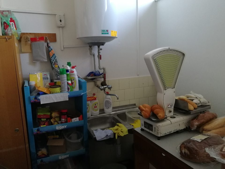 V priestoroch skladu sú potraviny, rôzne predmety, kartóny uložené chaoticky a neusporiadane.