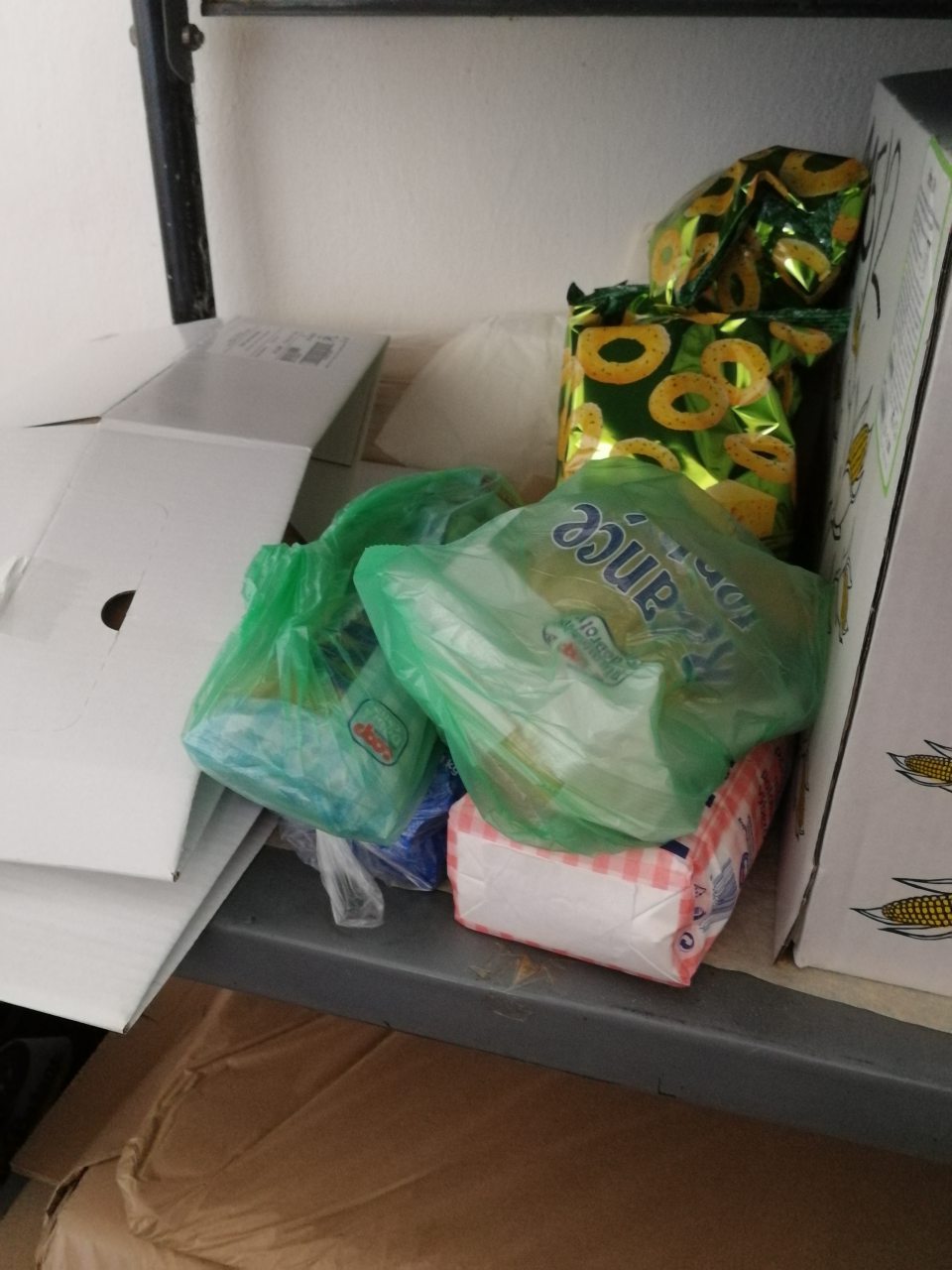 V priestoroch skladu sú potraviny, rôzne predmety, kartóny uložené chaoticky a neusporiadane.