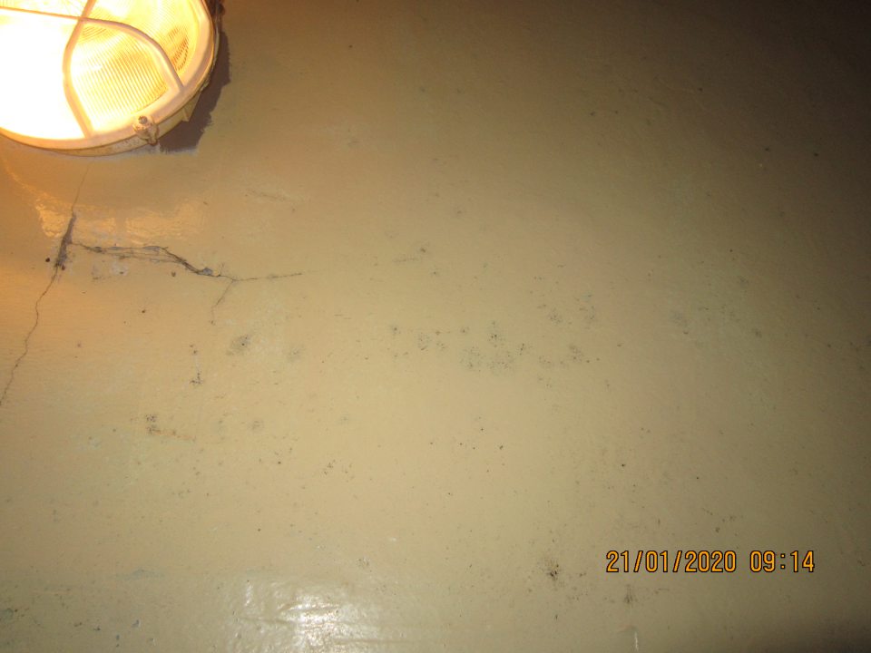 Olupujúci sa hygienický náter s výskytom plesne pod svietidlom nad dverami.