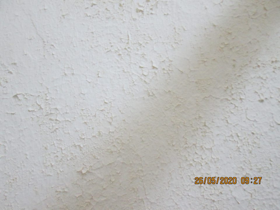 v sklade surovín v časti nad paletou s uskladnenými surovinami poškodený, olupujúci sa hygienický náter steny