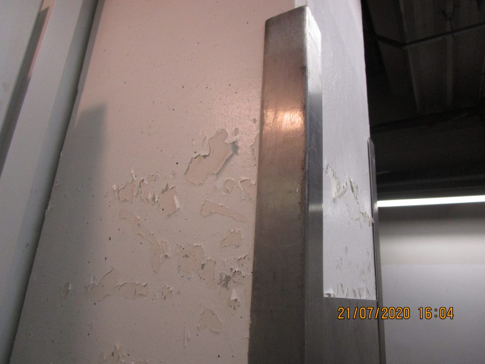 v zázemí prevádzky pri mraziacom boxe s uskladnenými hlbokozmrazenými potravinami opadaná omietka steny na troch miestach a znečistená podlaha 