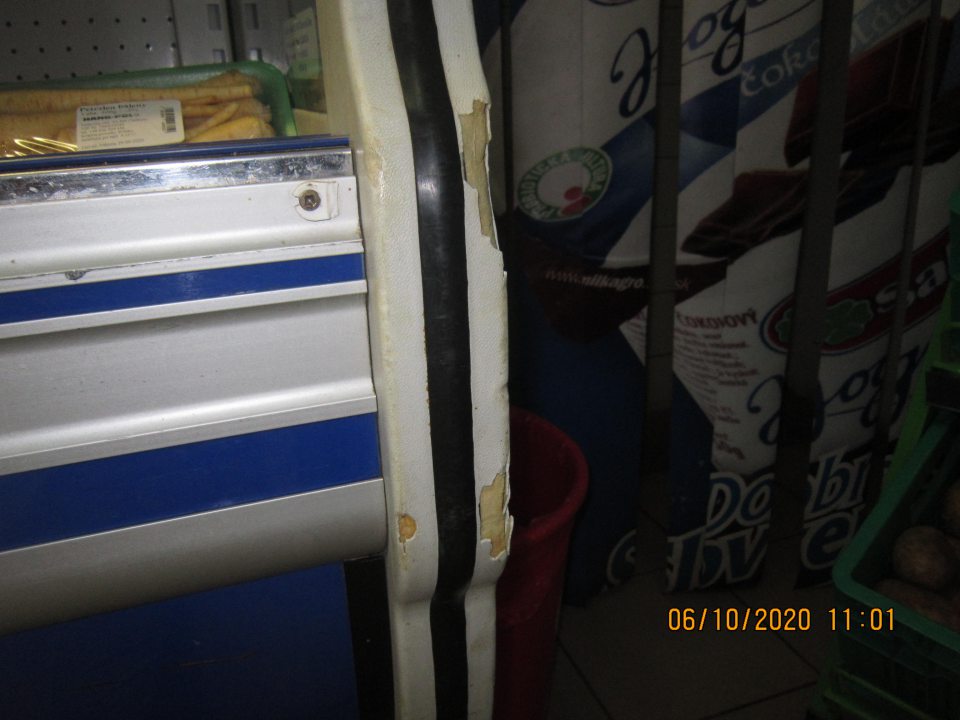 Regál chladiaceho zariadenia s uloženými uhorkami a kivi znečistený nánosom nečistôt a tiež zistený olupujúci sa povrchový hygienický náter na viacerých miestach o rozmeroch cca 60 cm x 2 cm, 8 cm x 1 cm Bočná stena chladiaceho zariadenia - sklenená výplň v spodnej časti na ľavej strane znečistená starším nánosom nečistôt V spodnej časti chladiaceho zariadenia s uloženou zeleninou zistený nános nečistôt pod kovovou mriežkou aj okolo kovovej mriežky Predné bočné steny chladiaceho zariadenie poškodené, na pravej strane poškodený povrch s vylomenými časťami na troch miestach o rozmeroch cca 5cm x 1cm, 2cm x 1cm a 1cm x 1 cm a na ľavej strane vylomené povrchové časti na dvoch miestach o rozmeroch cca 1cm x 0,5cm a 2cm x 0,5 cm