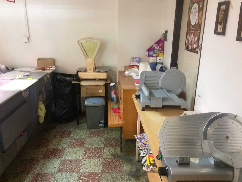 mäsový kútik bez prívodu teplej a studenej vody s množstvom nepotrebných vecí, na stene nad pultom, na ktorom sa nachádzajú stroje na krájanie mäsových výrobkov visia obrazy pokryté prachom 