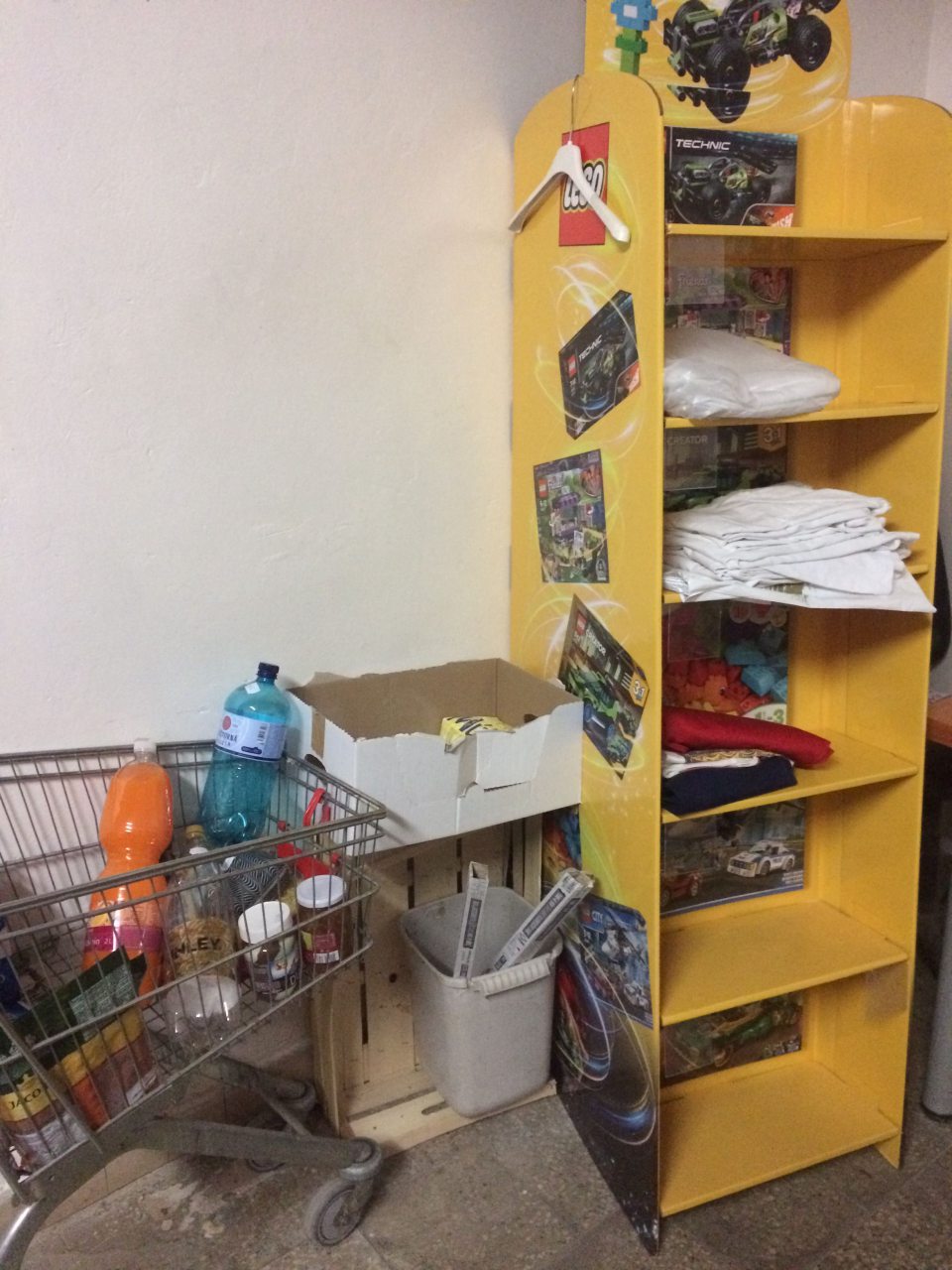 Oblečenie pracovníčok-čisté pracovné tričká uložené v provizórnom regály, chýbajú vhodné skrinky na odkladanie oblečenia