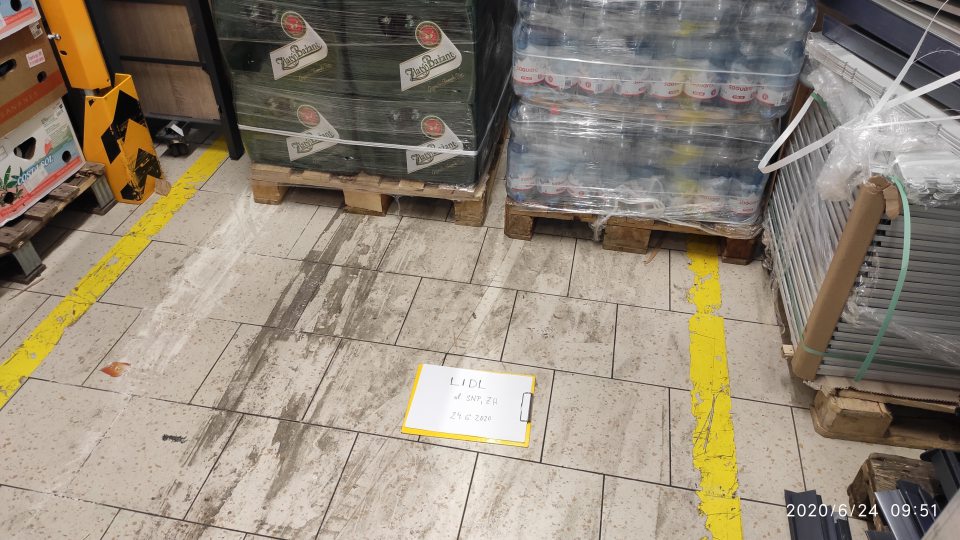 Podlaha v blízkosti chladiaceho boxu v zázemí znečistená vrstvou čiernej nečistoty, zvyškami potravín a vysypanou múkou.