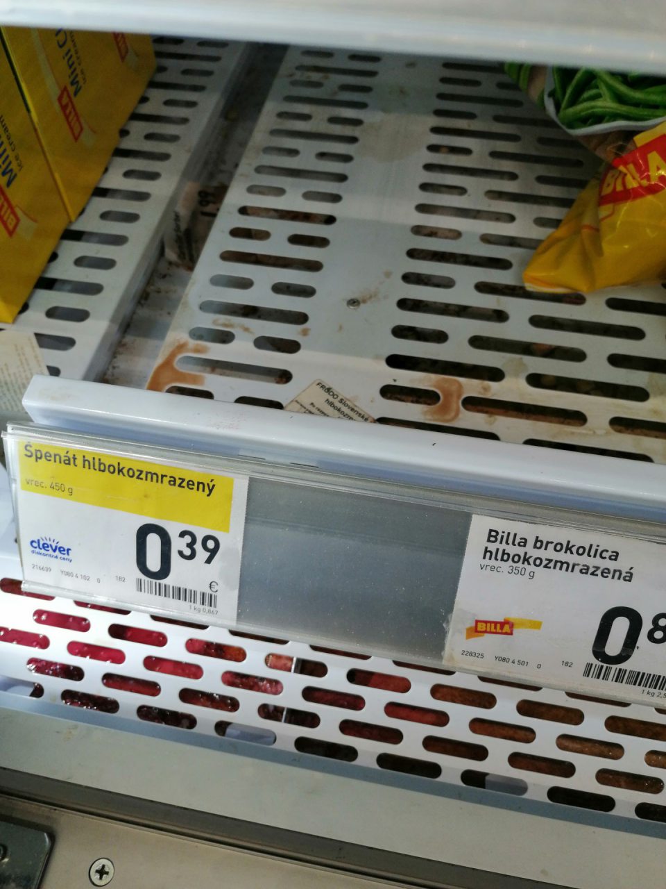 Znečistená spodná polica a priestor pod mriežkou v mraziacej vitríne.