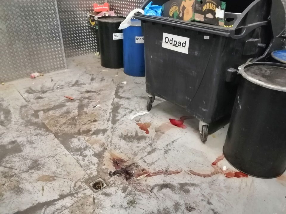 Znečistená podlaha v priestore s kontajnermi na komunálny odpad.