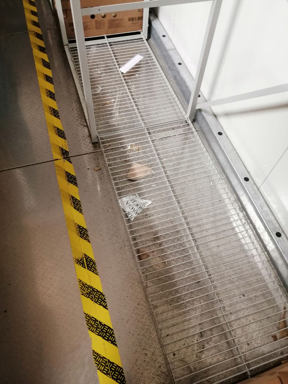 Nános nečistôt na podlahe pod kovovým regálom v mraziarensky sklad dopekov.