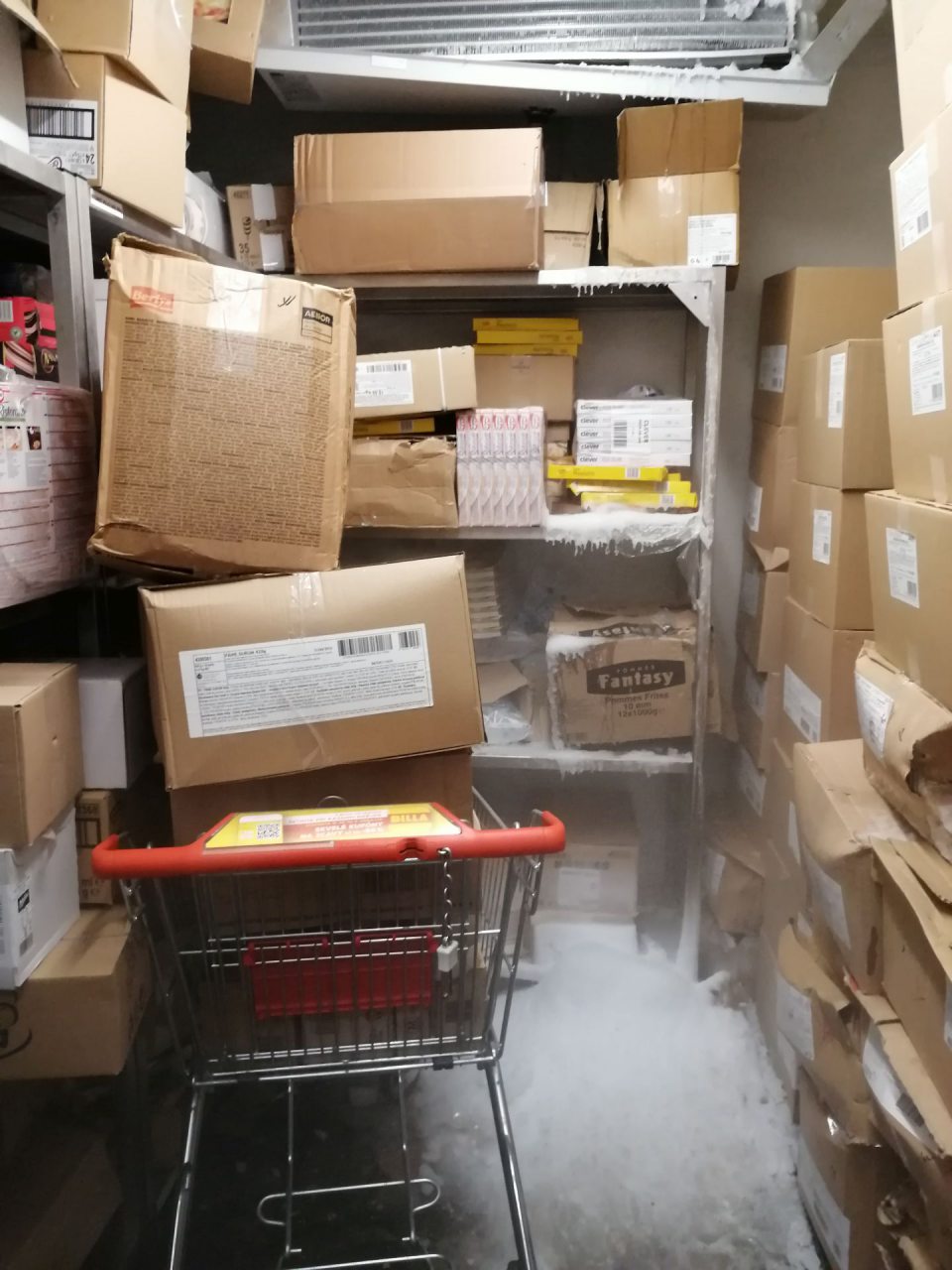 V mraziarenskom sklade výrazná námraza na chladiacom agregáte, hrubá vrstva ľadu na podlahe a krabiciach s tovarom.