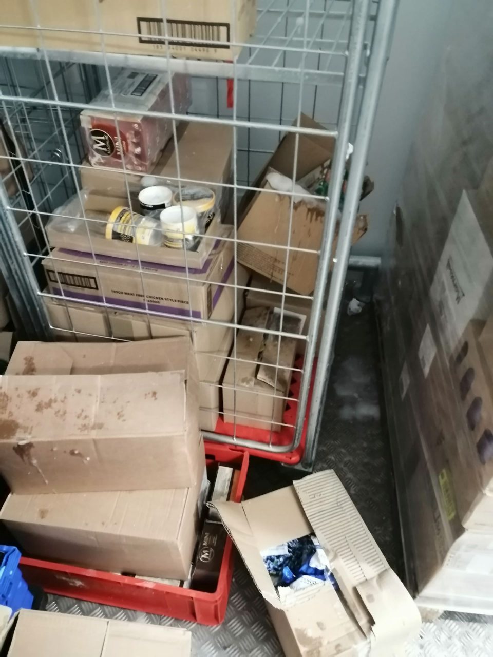 Námraza na podlahe, zamrznutý kondenzát na krabiciach s tovarom, rozhádzané krabice s tovarom na podlahe v sklade mrazeného tovaru.