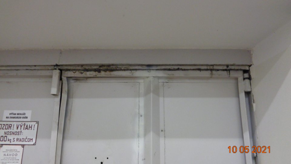 Dvere od výťahu znečistené hlavne na hornom okraji čiernou špinou.