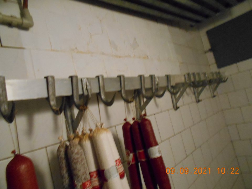  Olupujúci sa náter obkladačiek na stene zabudovaného boxxu s uchovávanými mäsovými výrobkami v zázemí predajne.