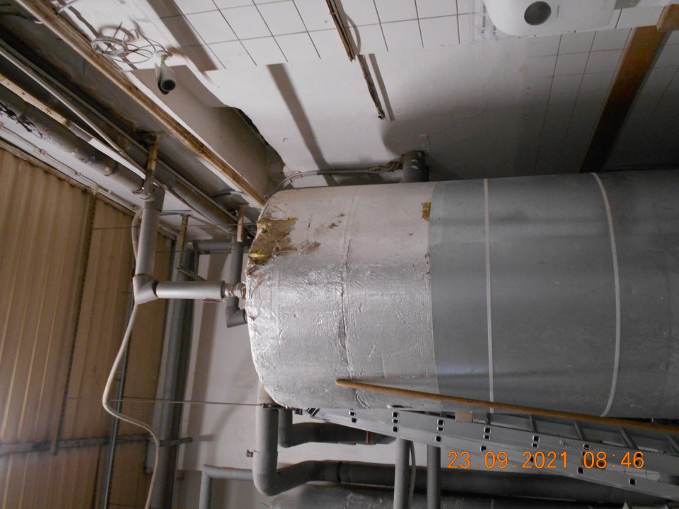 Poškodený povrchový obal nádrže na teplú vodu vo výrobnej časti prevádzky pri kysiarni (vyčnievajúca sklenná vata). 