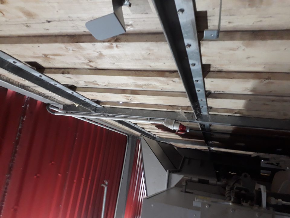 Na drevenom obklade v priestore lisu nahromadené visiace pavučiny so zachyteným prachom.