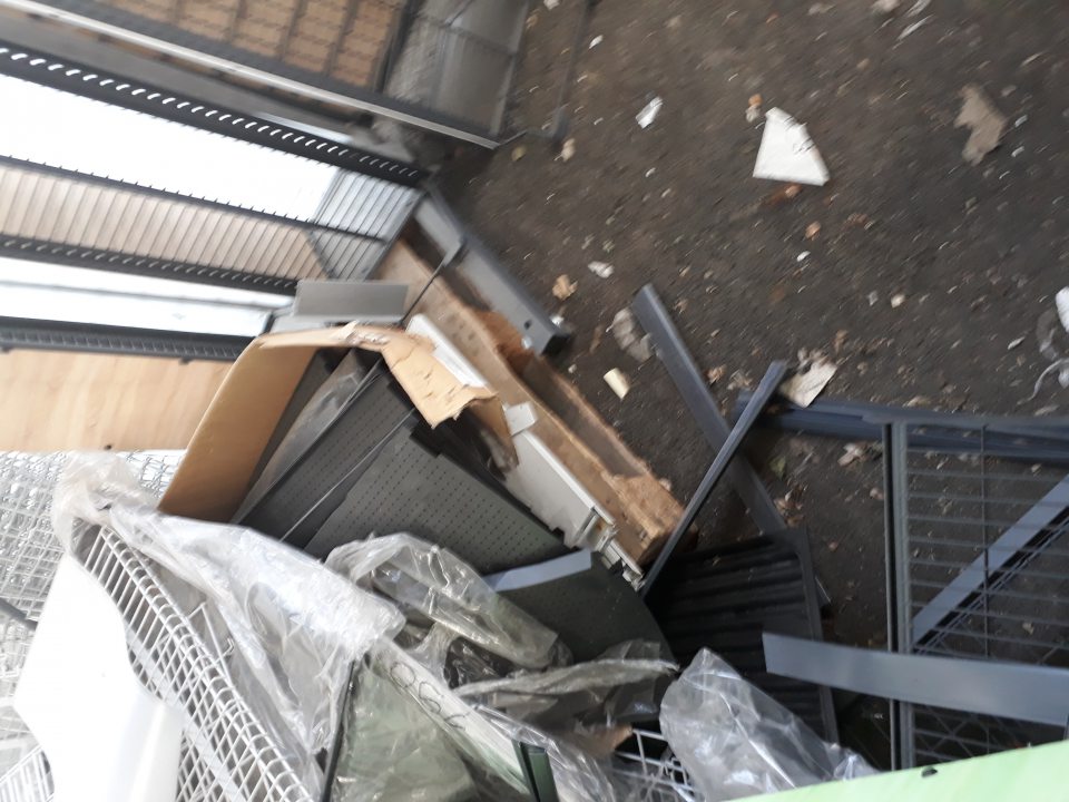 Na príjmovej rampe vo vonkajšom prostredí sú umiestnené 2 kovové klietky s nepoužívaným náradím a vybavením, vedľa klietok nahromadený rôzny odpad z obalov potravín.