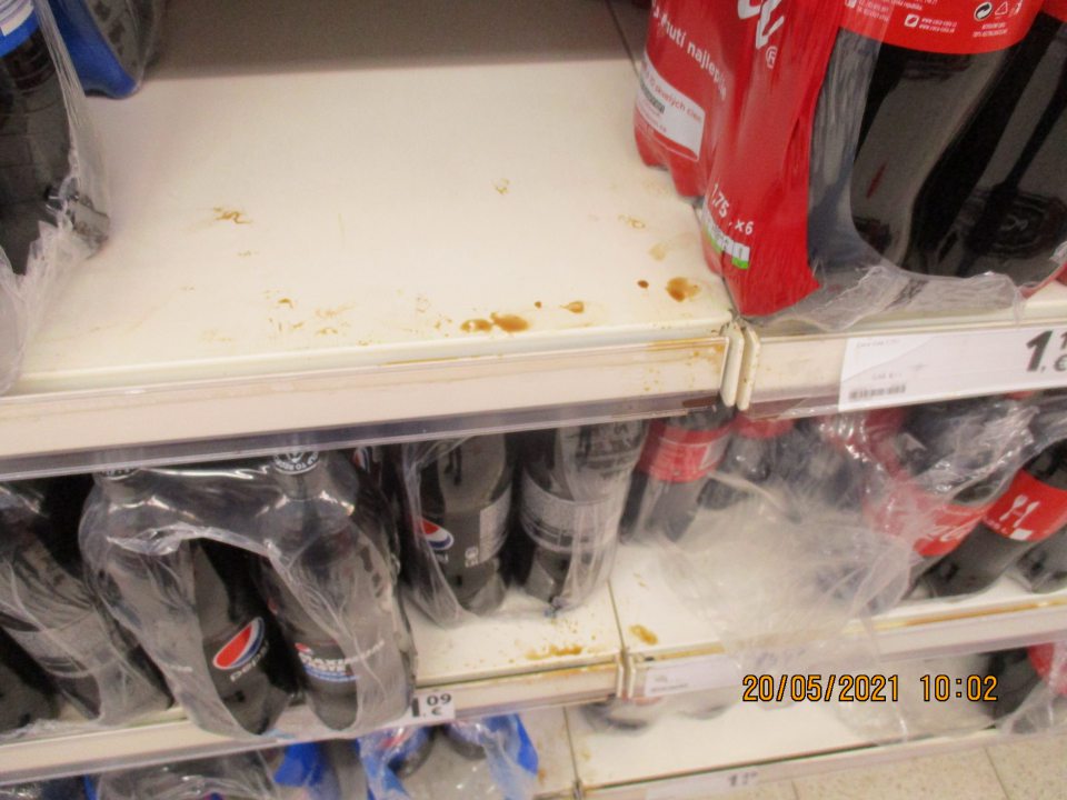 Znečistený regál s nealko nápojmi. 