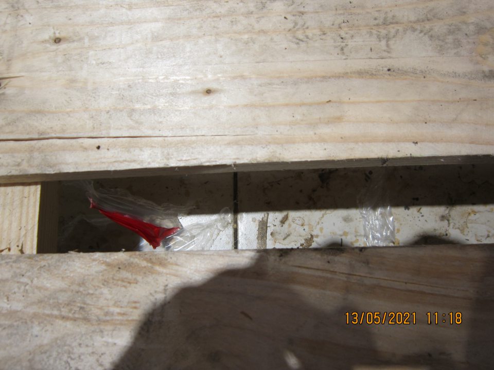 Znečistená podlaha pod paletami s uloženými nealkoholickými nápojmi na predajnej ploche- prach, zbytky obalového materiálu, triesky, nánosy zaschnutej špiny.