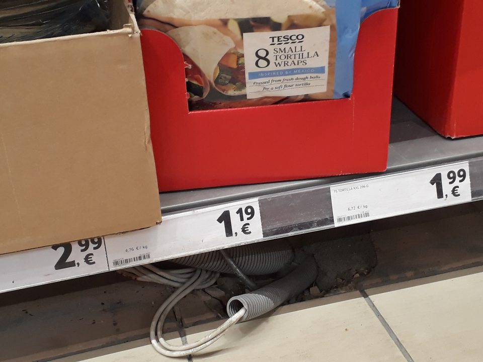 nezabezpečené prekrytie kabeláže pod regálom s pekárenskými výrobkami na predajnej ploche