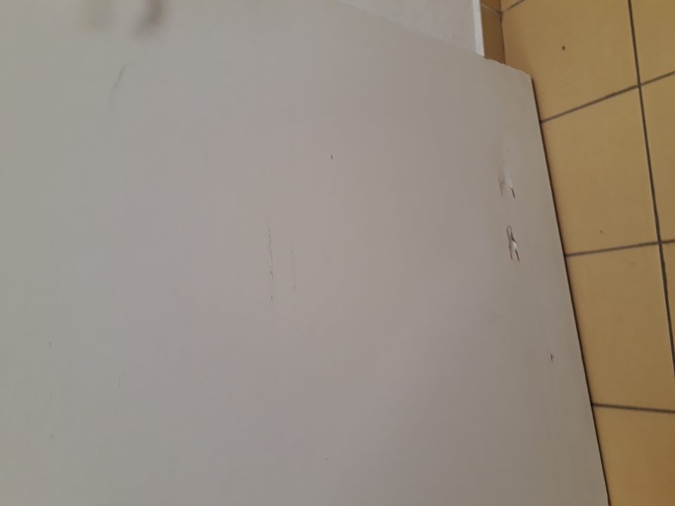 Porušená celistvosť povrchu dverí v spodnej časti vedúcich do zázemia predajne.