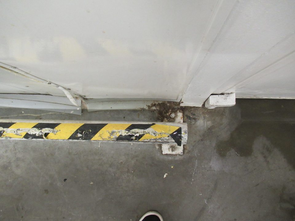 Poškodená celistvosť povrchovej úpravy "dorazovej" kovovej konštrukcie nachádzajúcej sa popri stenách v zázemí.
