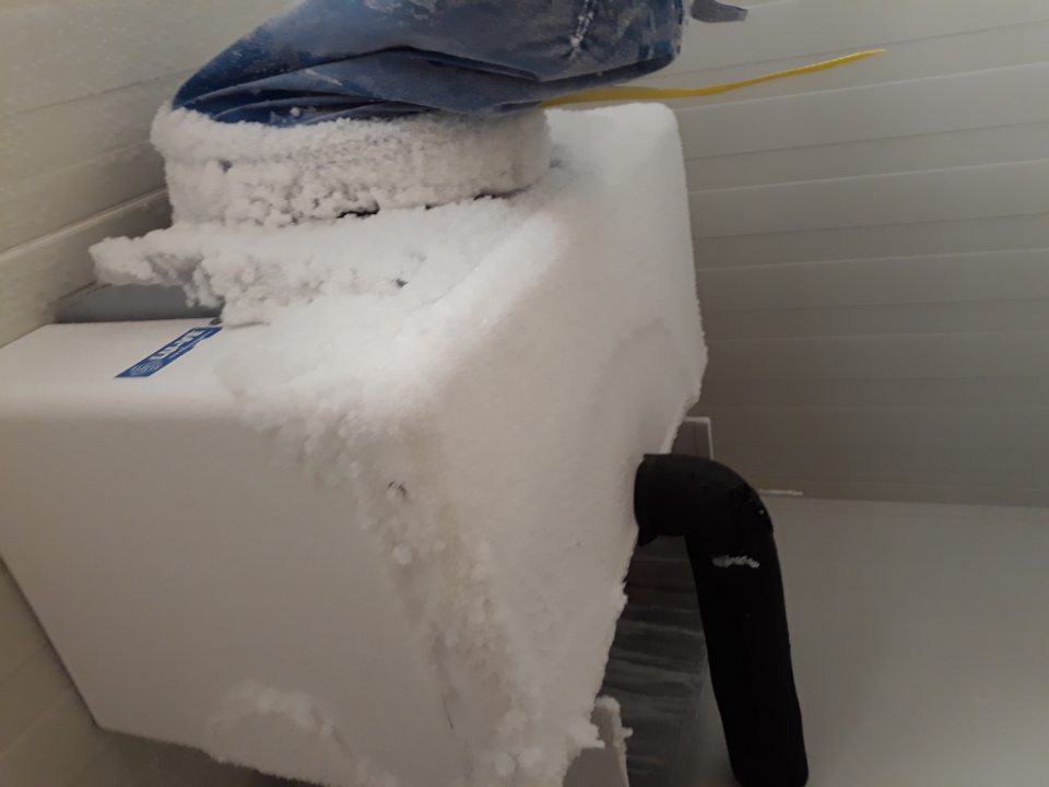 Súvislá vrstva namrznutého ľadového povlaku na mraziacej jednotke v sklade mrazených pekárskych polotovarov.