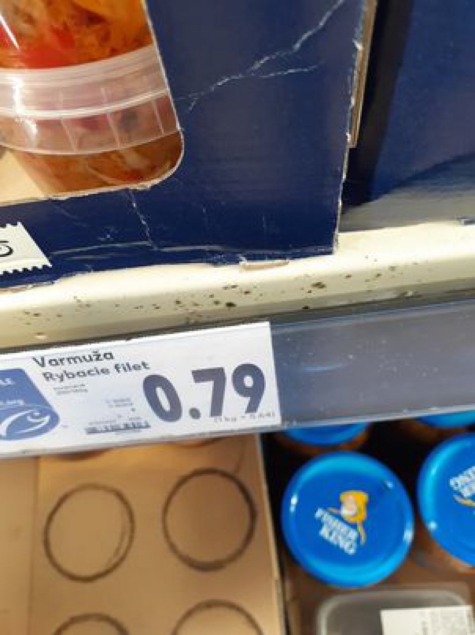 Znečistené chladiarenské zariadenie s vystavenými lahôdkarskými výrobkami na predajnej ploche.